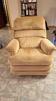Front view of beige corduroy-like upholstered La-Z-Boy rocking recliner chair showing padded armrests and segmented cushioned backrest.