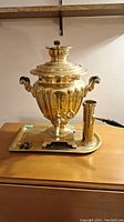 Front view of brass samovar on tray with chimney tube at right