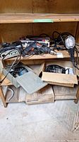 Lot of power tools and lighting on basement shelves, includes drills, jigsaw, trouble light, pump and box with power tool.