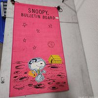 Front view of Snoopy bulletin board showing Snoopy in astronaut ensemble with stars and doghouse on a red background