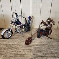 Photo showing both vintage folk art motorcycle figures: Harley Fatboy metal model and brass motorcycle with rider