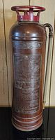 Full view of the antique brass fire extinguisher showing overall shape and patina.