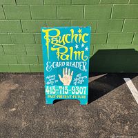 Front view of the sandwich board sign against a green wall showing all text and design