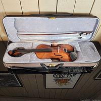 Open violin case displaying violin and bow inside, showing condition and interior compartments