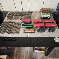 Photo showing all the train cars and curved and straight track pieces arranged on a table.