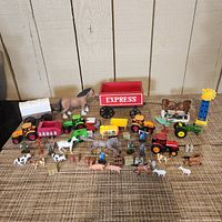Wide shot showing entire lot of farm and Wild West toys including animals, tractors, wagons, and figures arranged on carpeted surface with wooden background.
