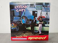 Front cover of Stray Cats 'Built for Speed' vinyl LP record showing band members by classic cars