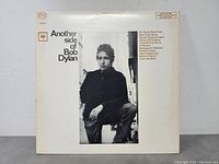 Front cover of 'Another Side of Bob Dylan' LP showing black and white photo of Dylan sitting outdoors.