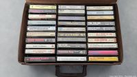Photo showing the cassette tapes arranged in a carrying case with visible spine labels of various rock and pop artists.