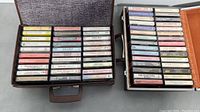 Photo of two boxes filled with cassette tapes showing a variety of music genres and artists, with visible cassette labels.