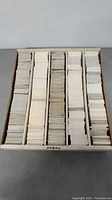 Top-down view of a large box filled with stacks of hockey trading cards sorted in rows.