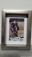 Front view of the autographed photo showing Johnny Bower in his hockey goalie uniform inside a silver frame.