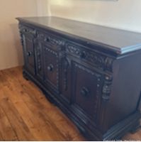 Front angled view showing three carved doors, decorative columns, and round wooden knobs