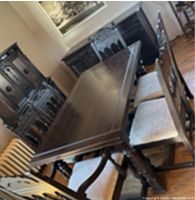 View of the dark stained wooden dining table with four side chairs on one side and captain chairs at the ends in a dining room setting.