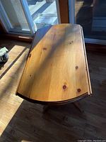 Top-down view of the wooden table top showing wood grain and finish with two drop sides folded down.