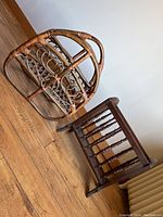 Two wooden magazine racks shown on wooden floor against plain wall, one dark stained spindle design rack and one natural rattan curved rack