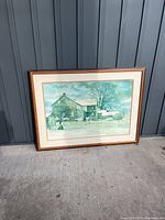 Framed picture, leaning against a dark wall outside, showing the entire frame and picture content.