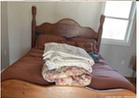 Front view of queen bed with mattress and folded blankets on top