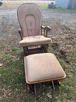 Front view of wooden rocking chair with beige cushions along with matching rocking ottoman on grass outdoors.