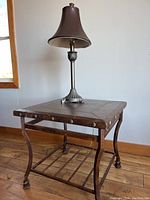 Side table with leather top, metal frame, and lower shelf with lamp on top