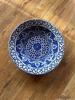 Top view of ceramic bowl with intricate blue floral and scrollwork patterns on white background
