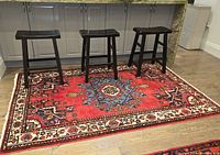 Rug under kitchen island with three black wooden stools