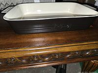 Side view of rectangular stoneware baking dish showing brown exterior with glossy finish and integrated handles.