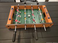 Top angled view of mini foosball table showing player rods and scorekeepers.