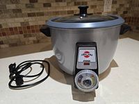Full view of Pars Khazar 8-cup rice cooker with power cord and glass lid on beige countertop with tiled backsplash.
