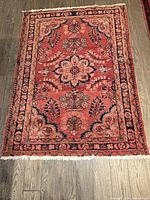 Full view of the Persian rug showing the floral design in the center and border.