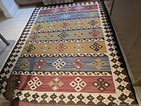 Full top down image showing the entire Persian Kilim rug with geometric pattern, color bands and visible fringes at shorter ends.