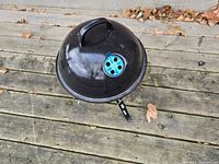 Top view of the closed dome lid showing black finish with a blue adjustable air vent and a handle.