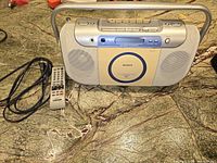 Front view of Sony portable CD player showing remote control, power cord, and top control buttons.