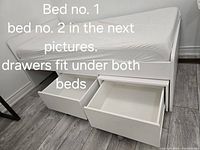 Twin size bed with two large drawers open underneath, white frame, mattress on top