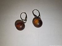 Photo showing both round amber earrings with silver lever back hooks on a white background.
