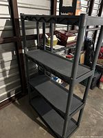 Side angle view of the black resin shelving unit showing four shelves, sturdy legs, and cross braces beneath the top shelf.