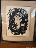 Framed silhouette artwork showing the full piece including tree, seated figure, and cottage with watermill wheel.