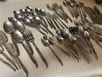 Wide shot of spread-out knives, forks, spoons on tabletop