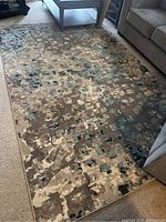 Full view of the rectangular Safavieh Madison Modern area rug placed on carpeted floor in living room, showing the abstract pattern in blues, grays, and tans.
