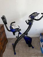 Left side view of Fitnation Flex Express Echelon Fit exercise bike showing padded seat with backrest, handlebar with digital display, and folding frame.