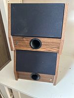 Another angle of two dbx Soundfield 3x2 RS Plus stereo speakers stacked vertically, highlighting the angled wooden side panels and bass ports, with black fabric grills on front.