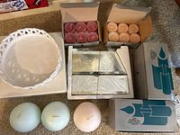 Photo of two ceramic candle holders, three ball candles in pastel colors, two boxes of tea lights in rose and peach colors.