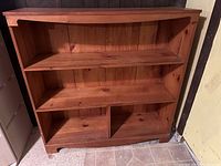 Front view of the pine wood bookcase showing three shelves with the bottom shelf divided into two compartments.