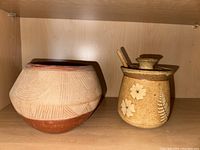 Both Native American San Juan pottery bowl and honey pot placed together on wooden shelf.