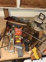 Overview of various hand tools and hardware including saws, levels, pliers, wire, staples, and a rotary organizer.