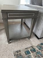 Close-up of one dark wood modern end table showing drawer detail with metal trim and tapered leg with metal cap.