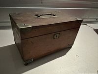 Wooden keepsake box angled side view showing metal corner protectors and front keyhole lock