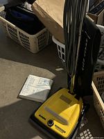 Yellow Eureka vacuum cleaner with black heavy duty cloth bag, showing power cord and suction dial.