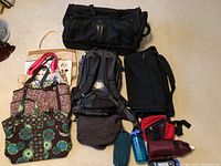 Photo displaying all bags including REI backpack, Tumi rolling duffel, garment bag, handbags, water bottles, and small shoulder bags.