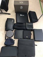 Overview photo showing various black and dark-colored cases including zippered and binder-style cases along with a gray metal file box